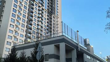 Un immeuble à plusieurs étages, doté d’un design moderne, avec une entrée imposante, une façade en verre et un escalier en métal.