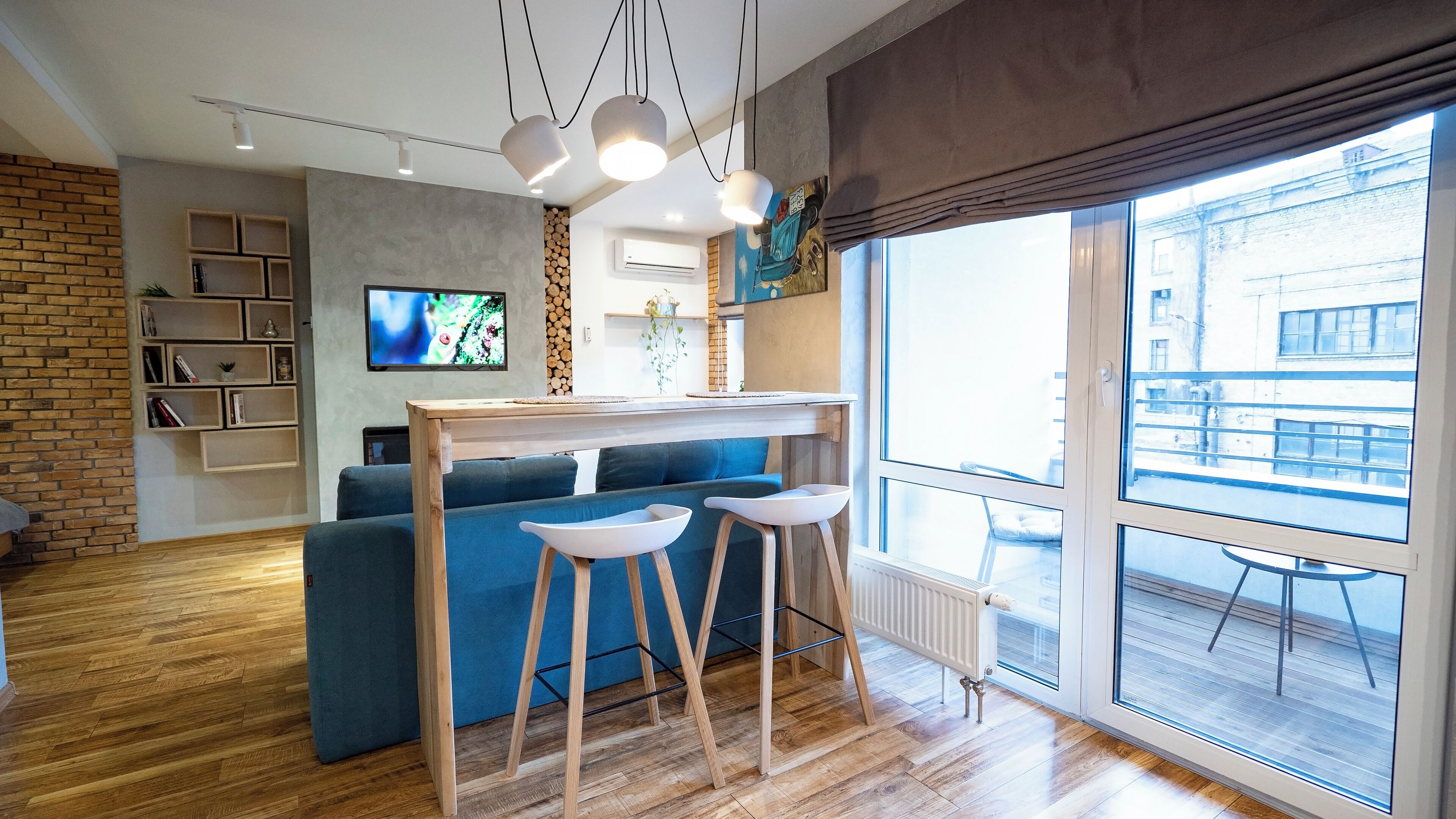 Un salon moderne avec un canapé bleu, un plancher en bois et un téléviseur fixé au mur.