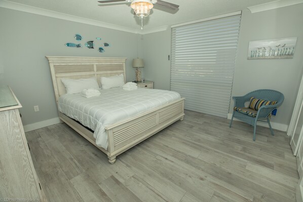A bedroom with a bed, nightstand, chair, and artwork on the walls.