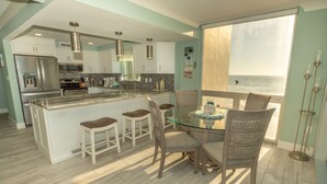 A modern kitchen with a central island, bar stools, and a dining table with chairs. - 2106 is a Gulf Front 3 bedroom unobstructed views by RedAwning (Destin)