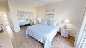 Un dormitorio con una cama grande, dos mesitas de noche con lámparas, un espejo y un cuadro en la pared.