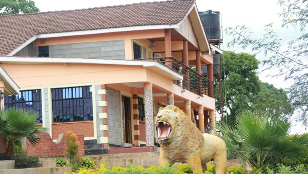 A two-story building with a balcony and a lion statue in front. - The Horizon Resort (Kapenguria)