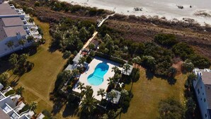 Luftaufnahme eines Resorts mit einem Swimmingpool, umgeben von Palmen und einem Strand.