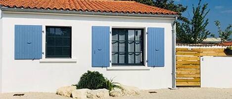 A single-story building with a tiled roof, blue shutters, and a wooden fence.