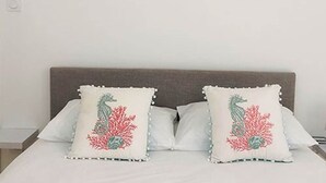A bed with two pillows featuring a sea creature design, a framed picture above the bed, and a plain wall. - LA MAISONNETTE, Gîte 5. Clos des Aigrettes, 30m from La Cotinière Port (ST PIERRE D'OLERON)