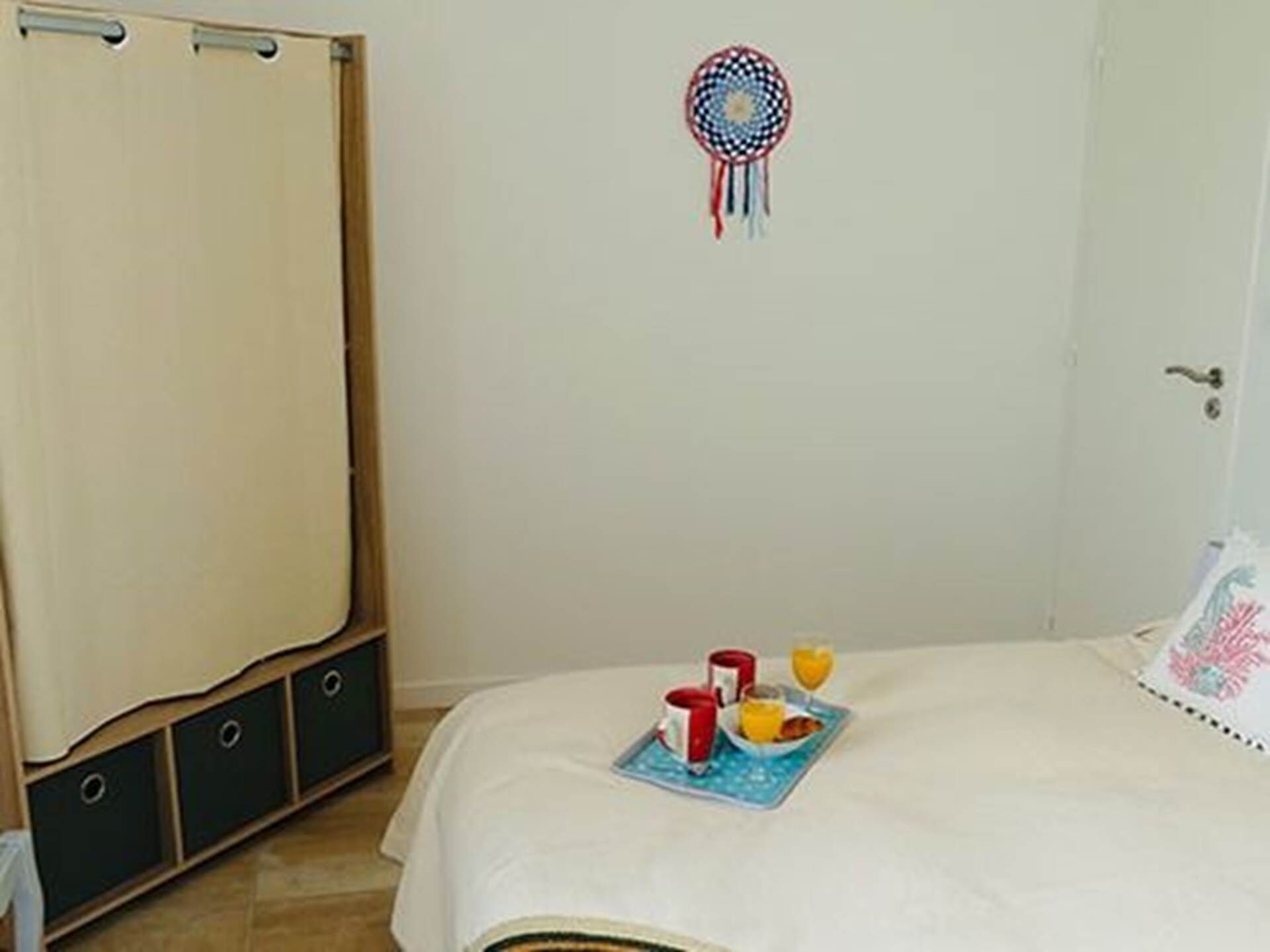 Een slaapkamer met een bed, nachtkastje, kledingkast en een droomvanger aan de muur.