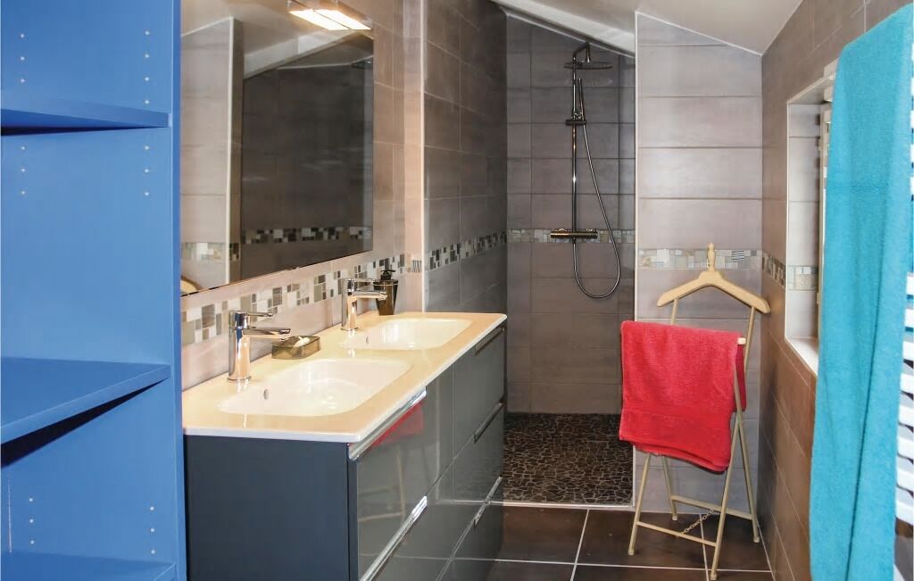 A modern bathroom with two sinks, a shower, and a towel rack.