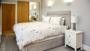 Ein Schlafzimmer mit einem Bett, Nachttischen, einem Spiegel und einer Tür.