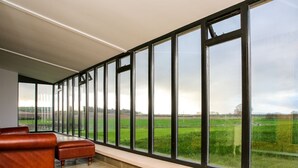 Ein Zimmer mit großem Fenster und Blick auf ein grünes Feld.