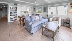 A spacious living area with a sofa, a coffee table, and a bookshelf. - "Commodores 101" | Corner Unit w/ Beach Views | Community Pool | Beach Chairs included (Santa Rosa Beach)