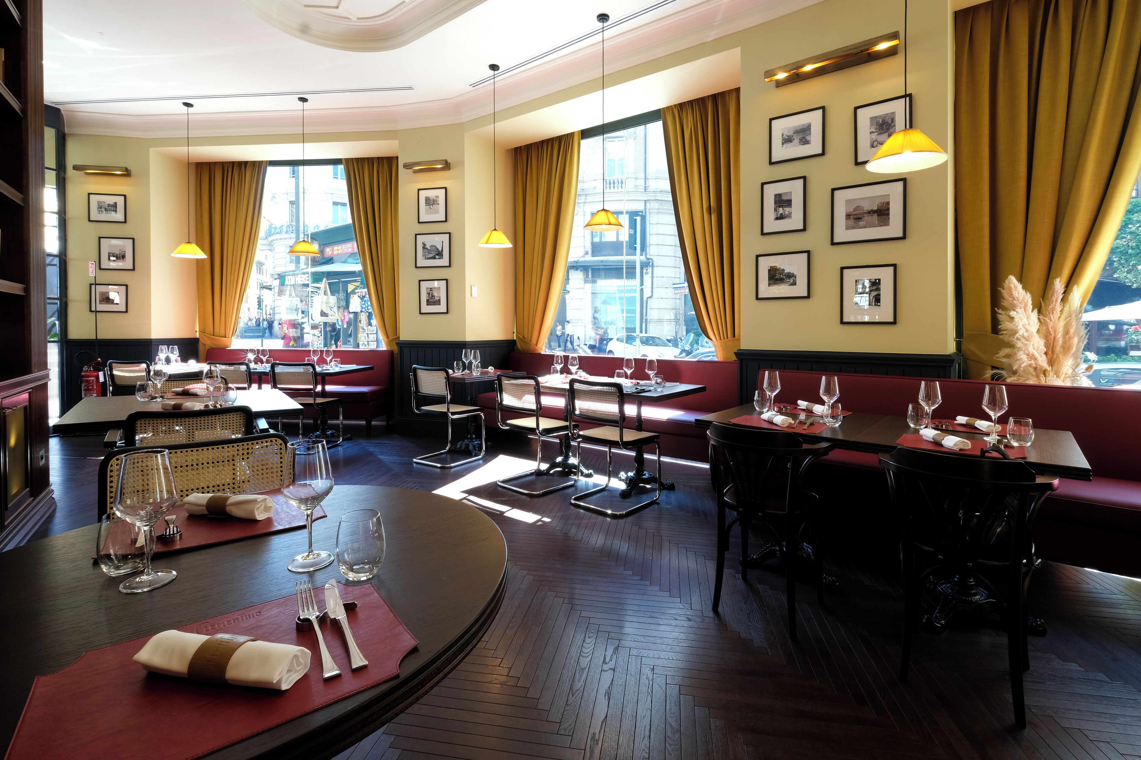Ein Restaurant mit Holzboden, roten Sitzkissen und Tischen, die mit Weingläsern und Besteck gedeckt sind.