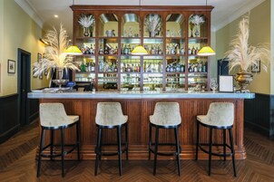 Angolo bar con un bancone in legno, tre sgabelli da bar e una vetrina piena di bottiglie.