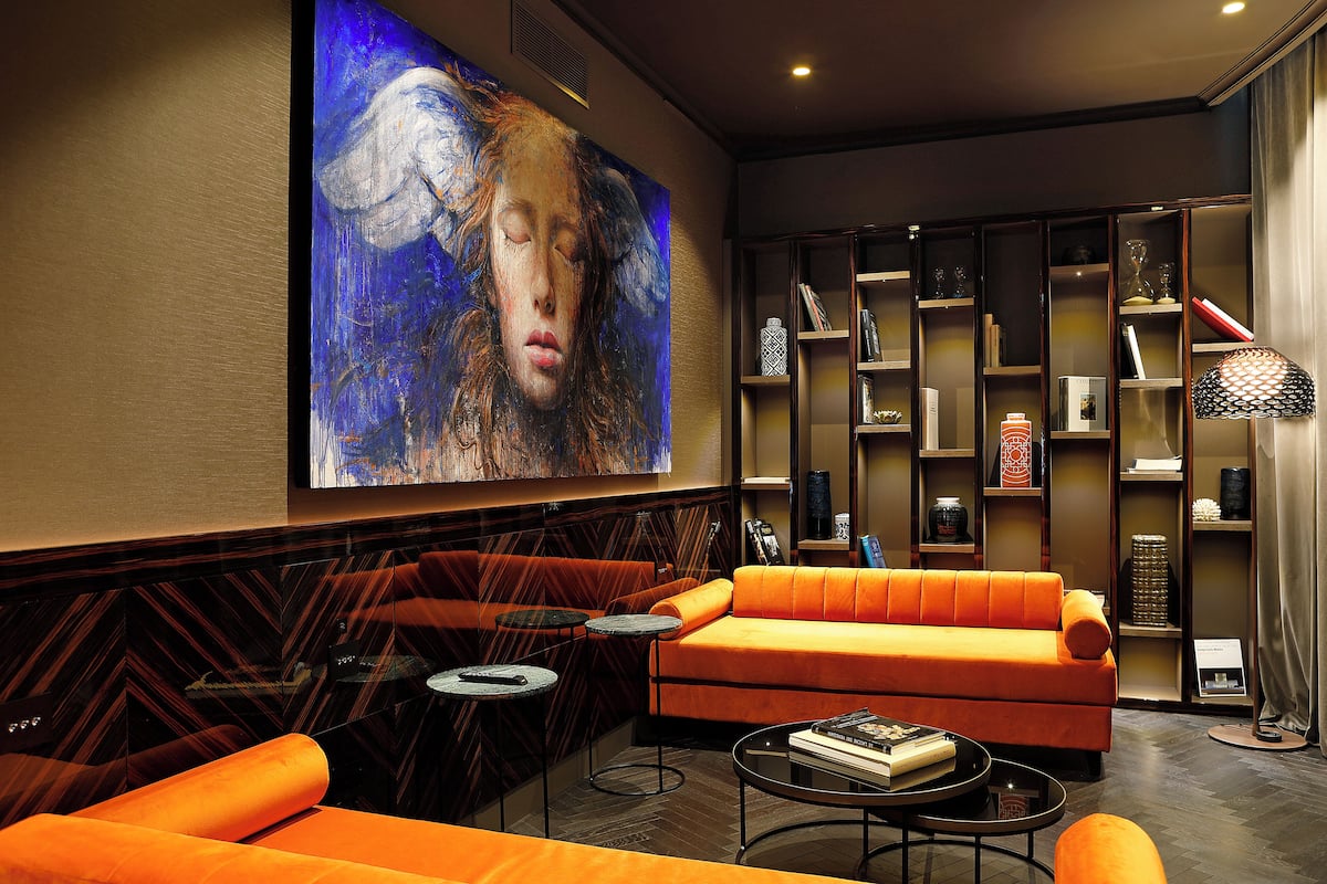 A modern living room with an orange sofa, a coffee table, and a bookshelf filled with books and decorative items.