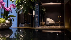 A modern room with a glass partition, a chair, a small table, and potted plants. - U-Visionary Roma Hotel (Rome)
