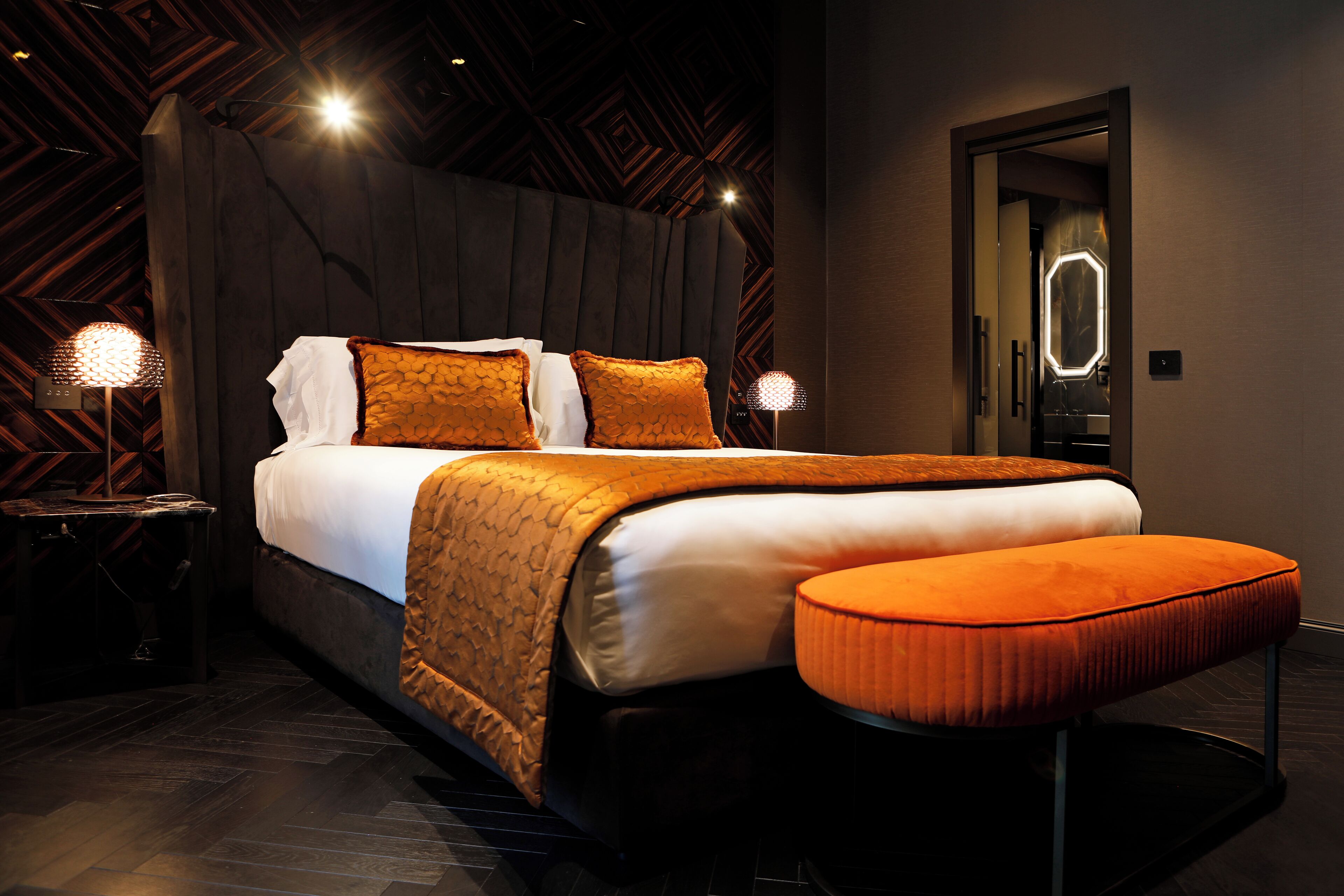 A modern bedroom with a large bed, a nightstand, and a bench.
