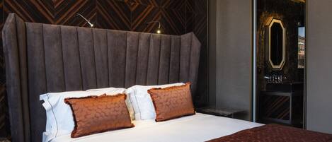 A modern hotel room with a large bed, a wooden-patterned headboard, and a mirror above the bed.