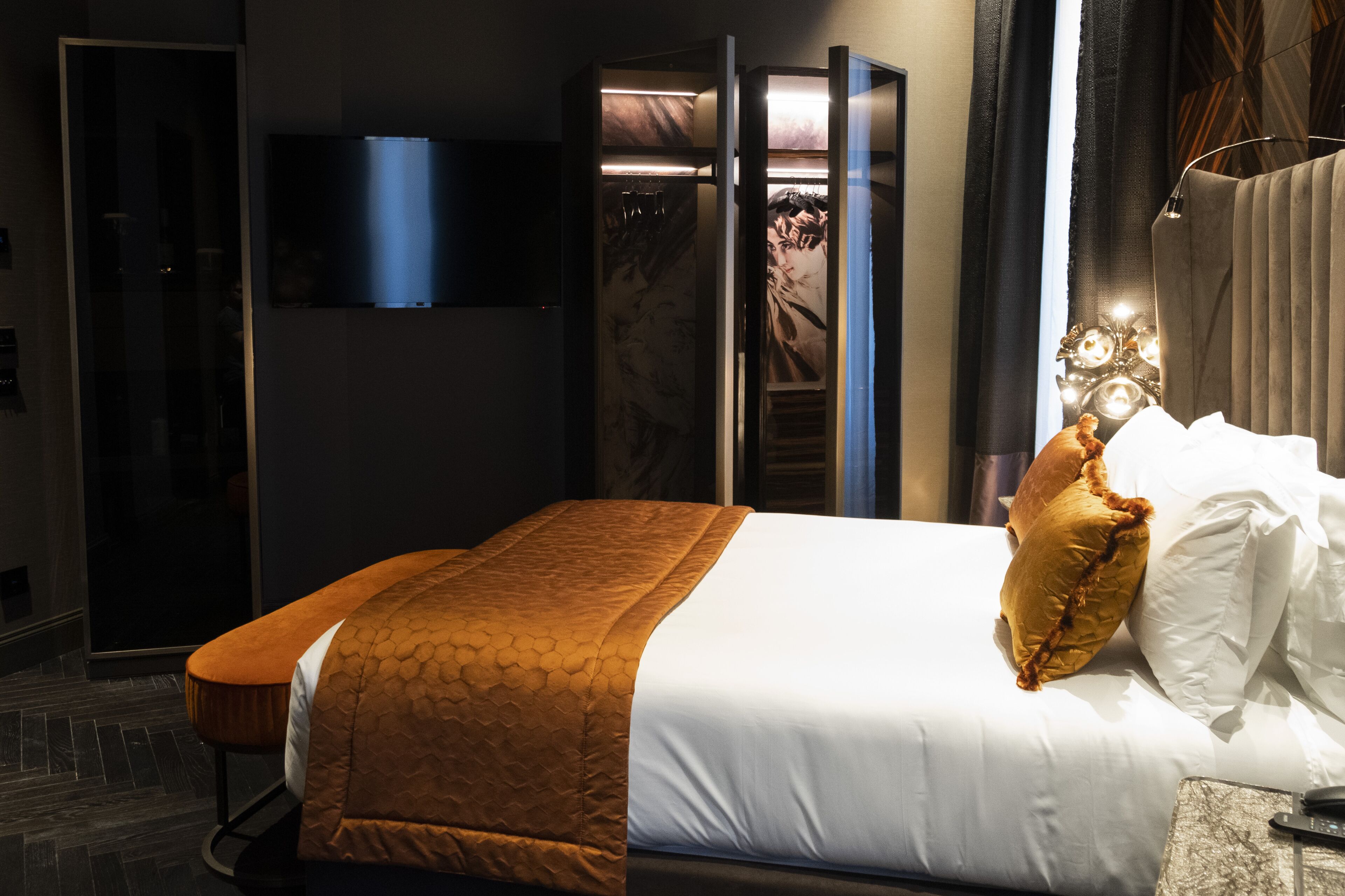 A hotel room with a bed, a television mounted on the wall, and a nightstand with a remote control.