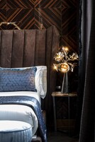 Una camera da letto con un letto, un comodino e una lampada a parete.