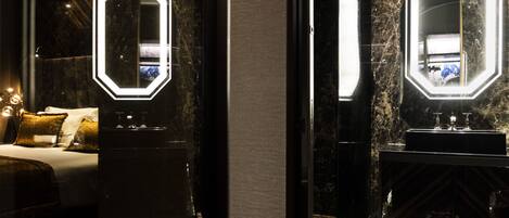 A modern hotel room with a large bed, a nightstand, a mirror with illuminated frame, and a marble floor.