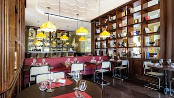 Un restaurant amb prestatgeries de fusta, seients vermells i llums penjants grogues.