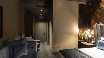A hotel room with a bed, a sofa, and a small table with a lamp.