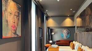 A hotel room with two beds, a large painting on the wall, a modern lamp, and a view of the city through the window. - U-Visionary Roma Hotel (Rome)