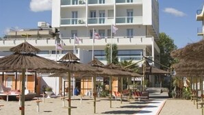 A beachside hotel with multiple balconies, thatched umbrellas, and a clear sky. - Hotel Igea Spiaggia (Bellaria-Igea Marina)
