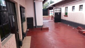 Un pasillo con piso rojo, puertas negras y pared blanca con el número 3.