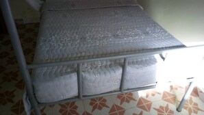 Una cama con estructura metálica, ropa de cama gris y dosel.