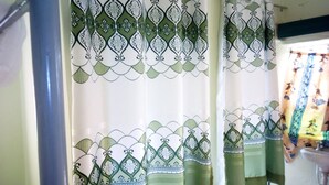 Un baño con cortina de ducha de estampado verde y blanco.