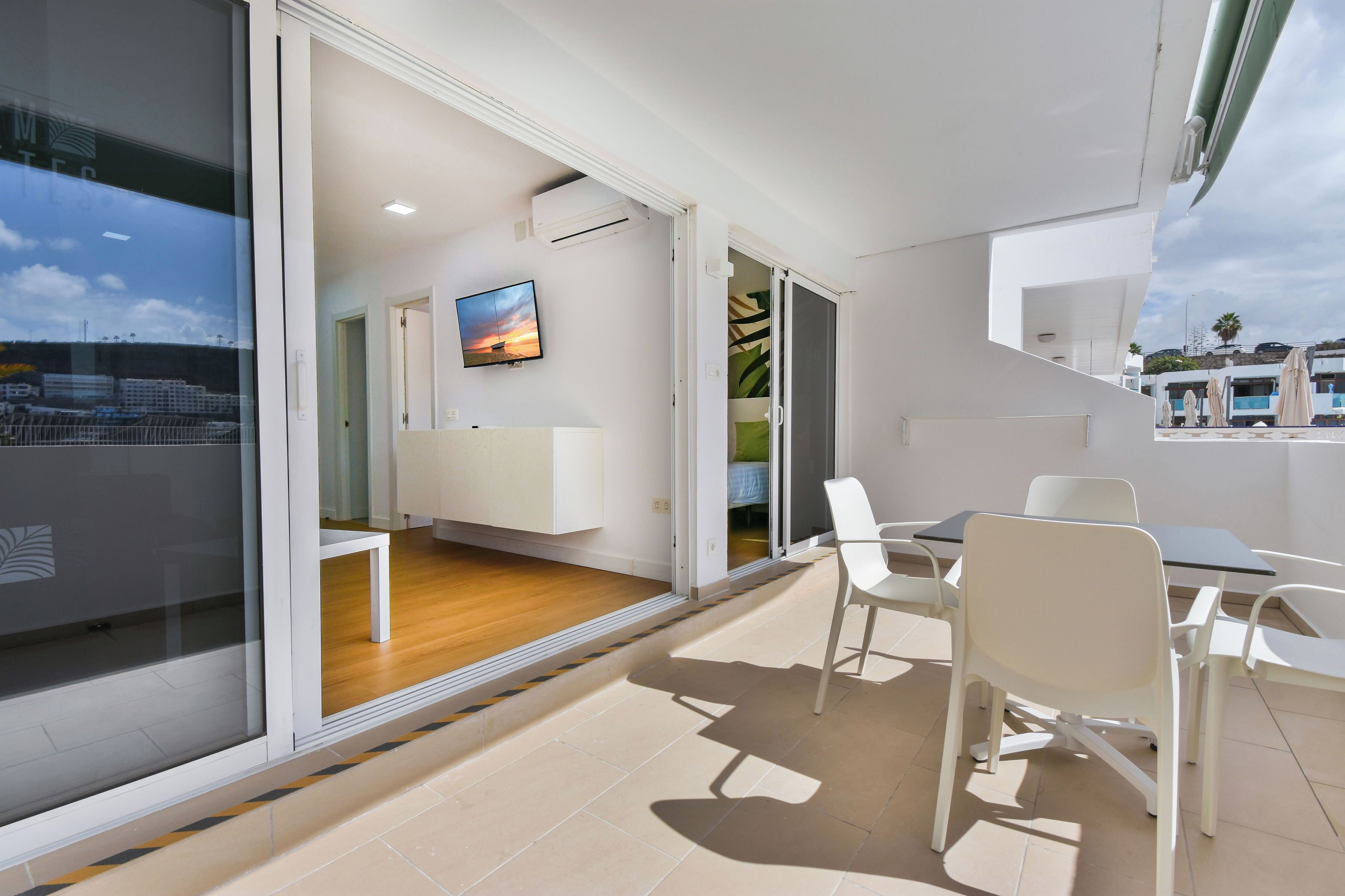 Habitación de hotel moderna con balcón, televisor de pantalla plana y vistas a la ciudad.