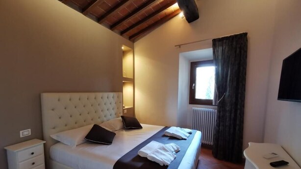 A bedroom with a large bed, a bedside table, a window, and a radiator. - Farmhouse 2: authentic Tuscan house (Dicomano)