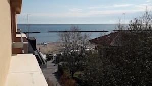 Ein Balkon mit Blick auf einen Strand unter blauem Himmel.