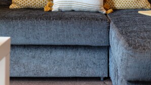 A grey sofa with patterned cushions and a painting of a boat on the wall. - Elliot Suite No3 - Donnini Apartments (Ayr)