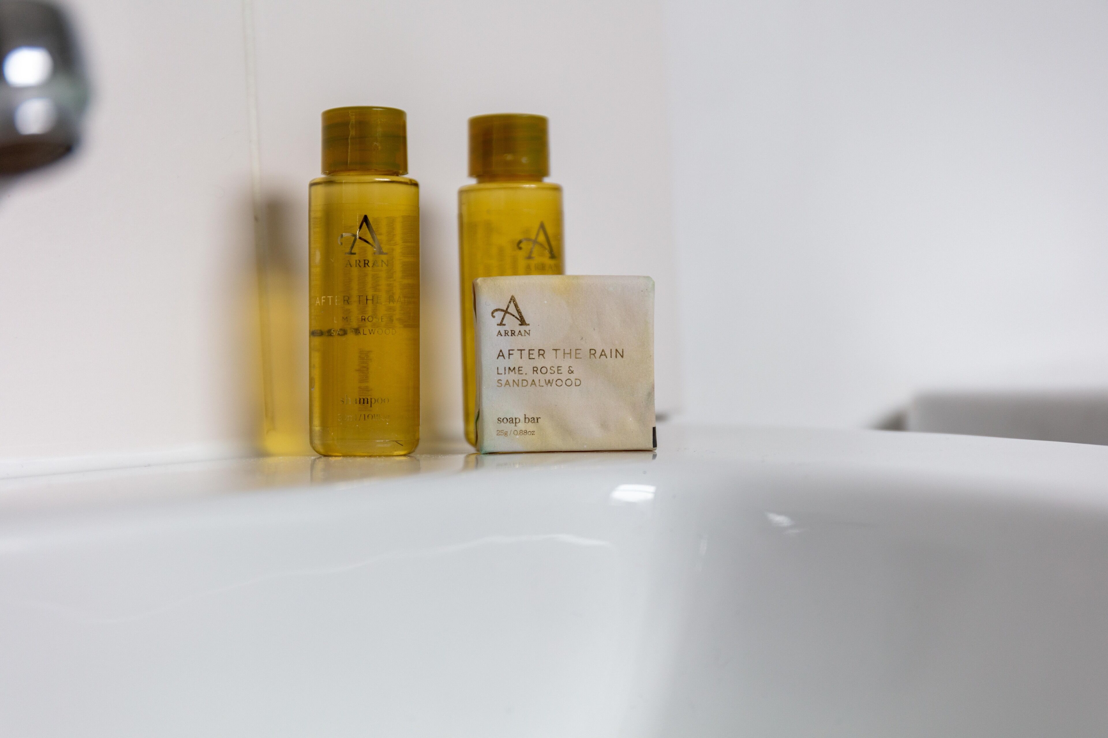 Two yellow bottles and a soap bar on a white surface.