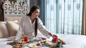 A hotel room with a bed, breakfast setup, and a decorative headboard. - Seven Seas Hotel (New Delhi)