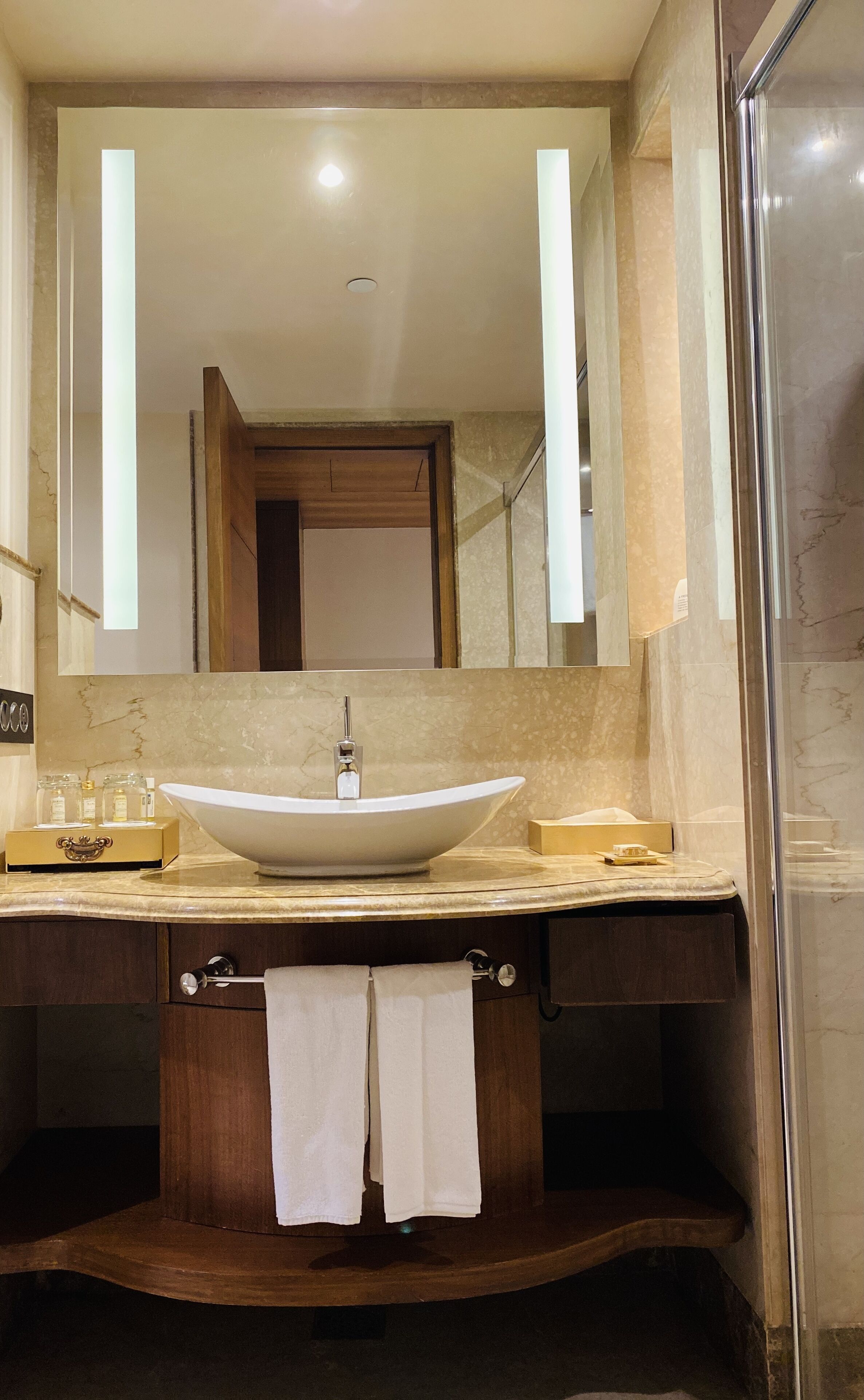 A bathroom with a large oval sink, a mirror, and a glass shower enclosure.