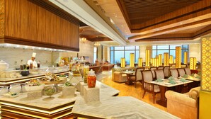 A modern hotel lobby with a marble reception desk, seating area, and large windows offering a view of the cityscape. - Seven Seas Hotel (New Delhi)