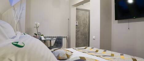 Una habitación de hotel con una cama, un escritorio, una silla, un televisor y una puerta.