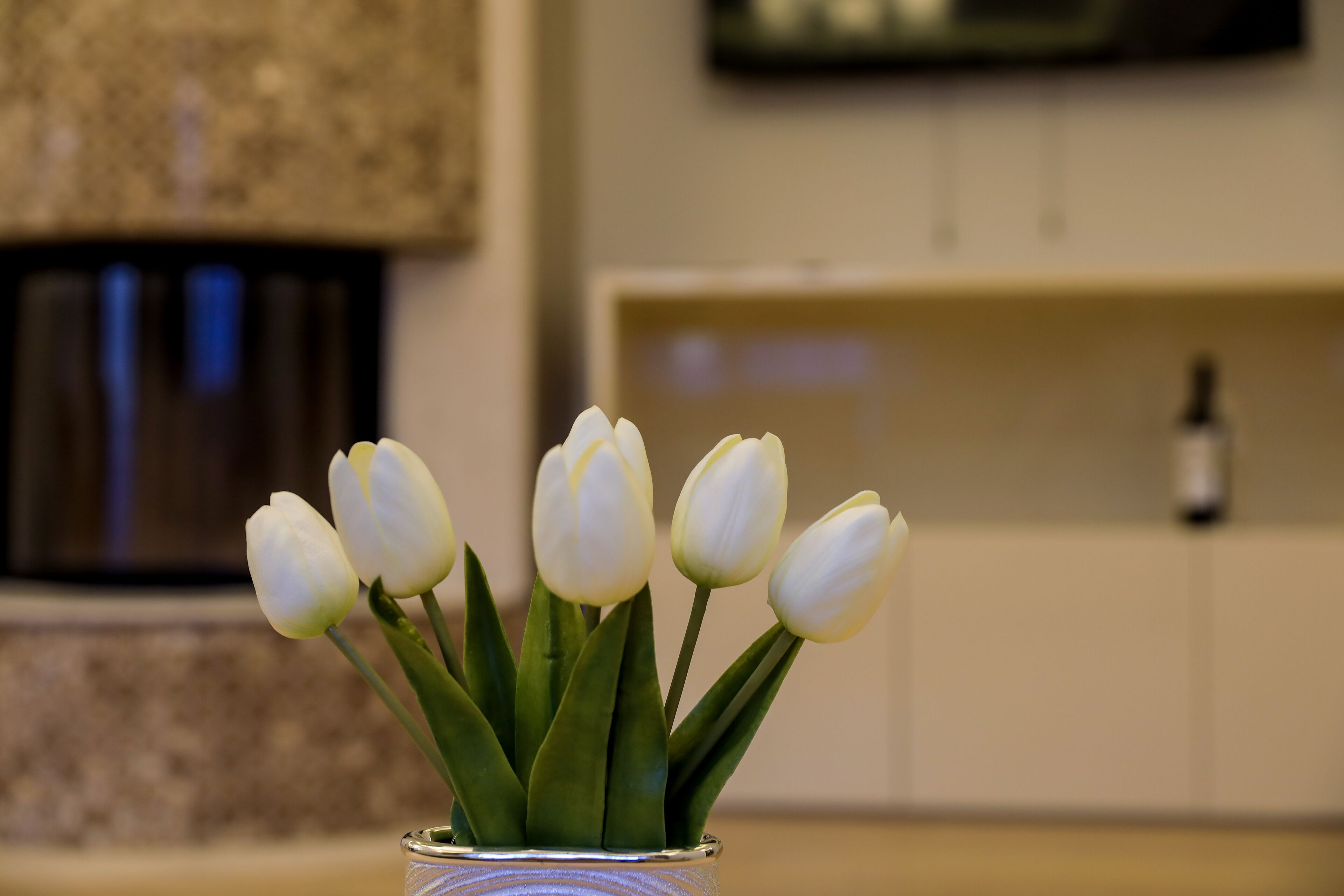 Un jarrón con tulipanes blancos sobre una mesa.