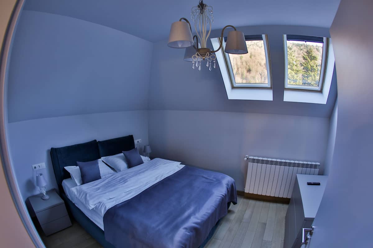 Un dormitorio con cama, mesitas de noche, un radiador y una ventana con vistas.