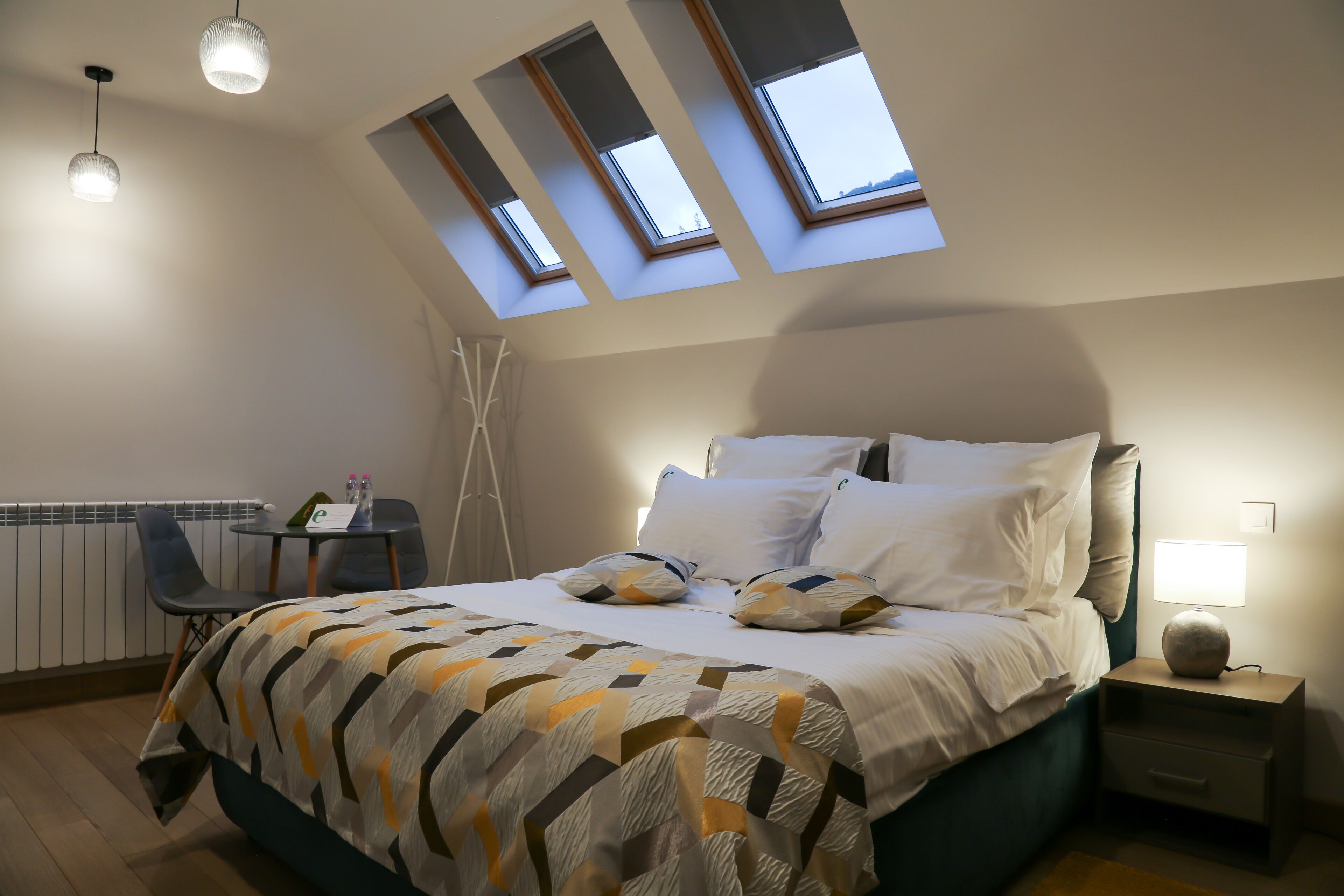 Une chambre à coucher avec un lit, un bureau et des fenêtres de toit.