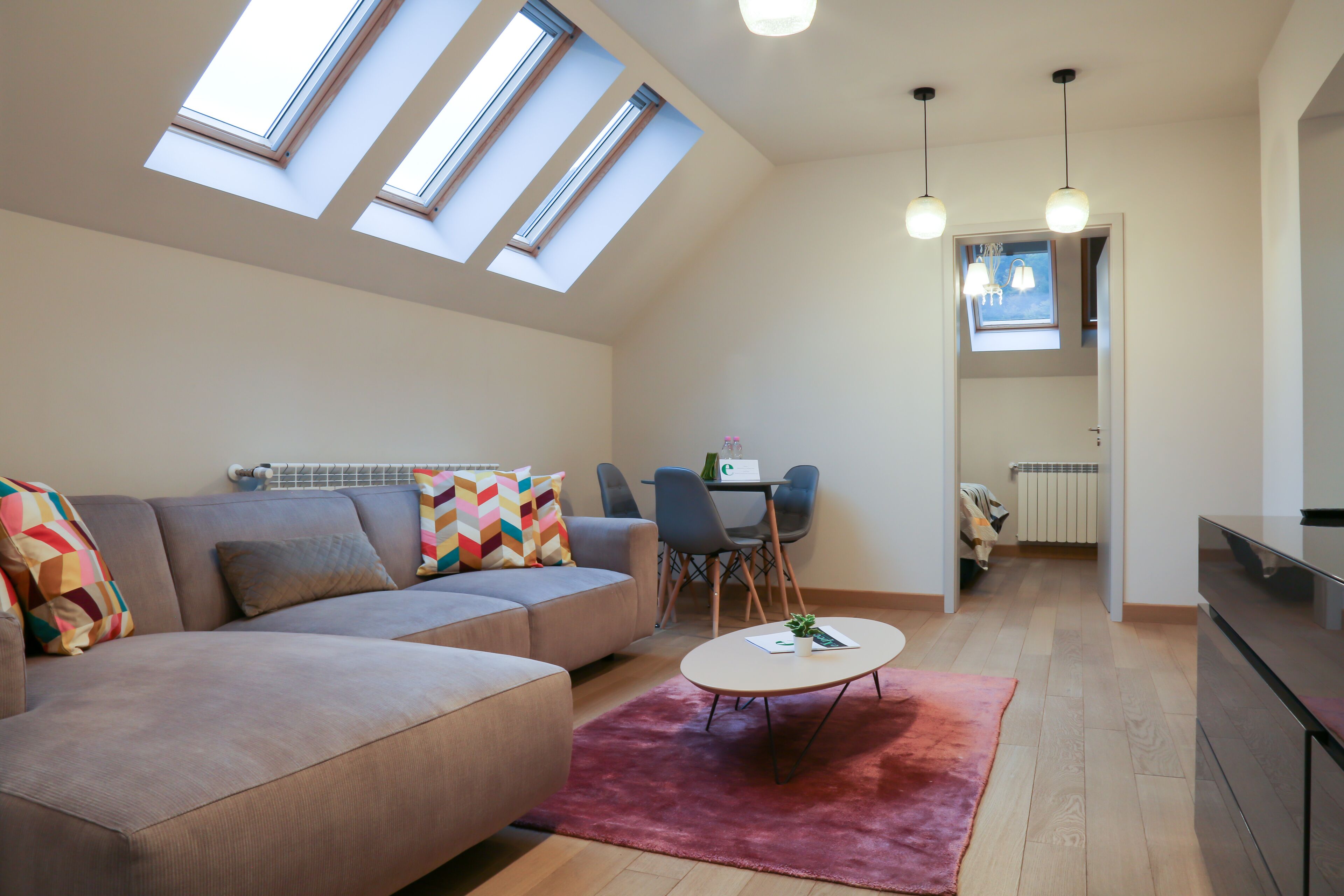 A modern living room with a sofa, a coffee table, and a dining area with chairs.