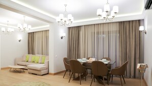 Uma sala de estar moderna com sofá, mesa de jantar, cadeiras e um lustre.