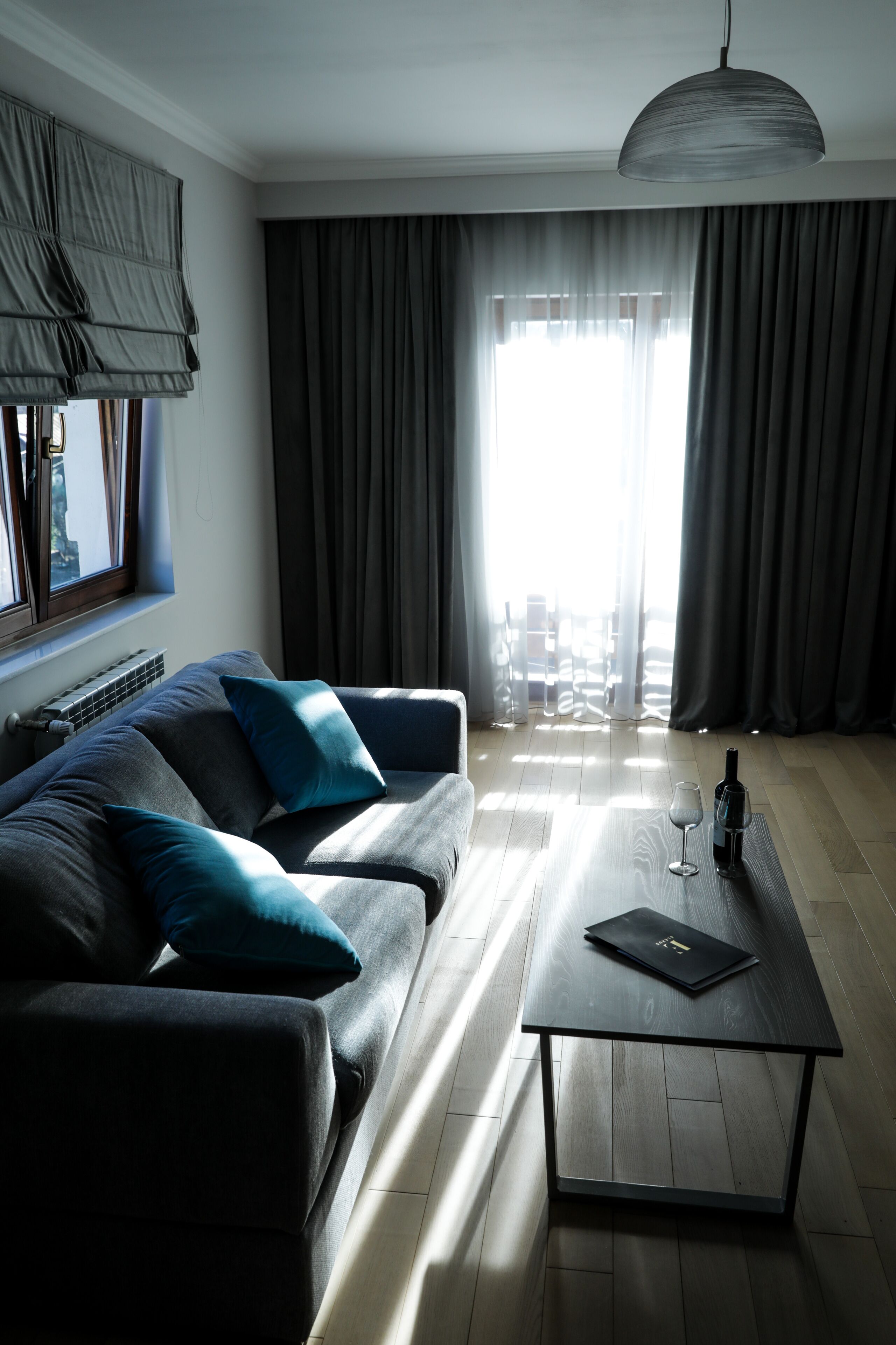 Ein modernes Wohnzimmer mit einer Couch, einem Couchtisch und Blick auf die Stadt durch große Fenster.