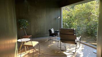 A modern room with a large window, a round table, two chairs, and a floor lamp.