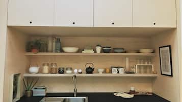 A kitchen with white cabinets, a black countertop, and various kitchen items like jars, a kettle, and a coffee maker.