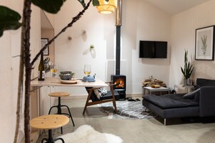 Una sala de estar acogedora con chimenea, un sofá y un comedor con taburetes.