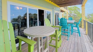 Un espace extérieur abrité, dot é d’une table et de chaises, d’une porte-fenêtre coulissante et d’une terrasse en bois.