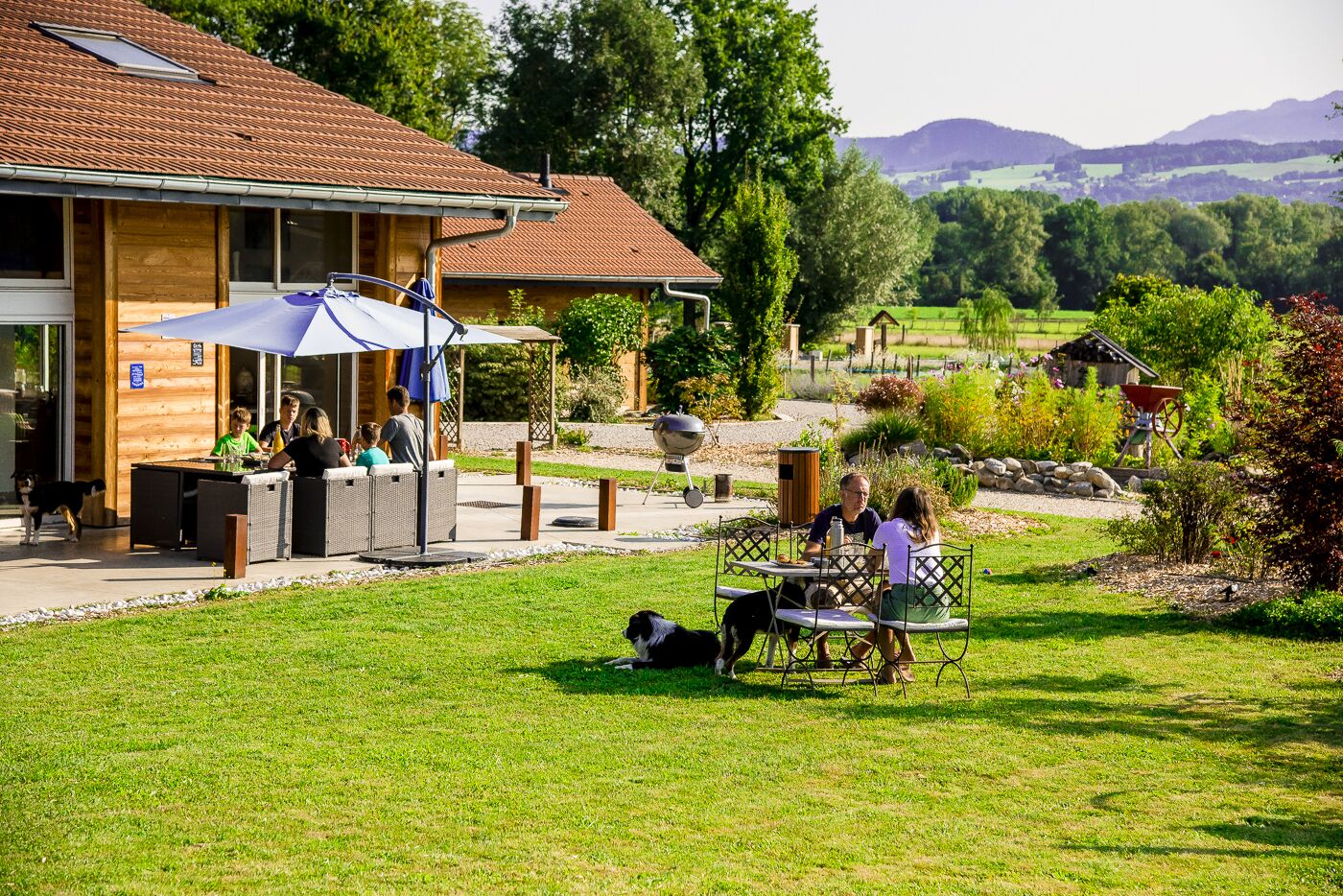 An outdoor dining area with tables and chairs, a covered seating area, and a view of the surrounding landscape.